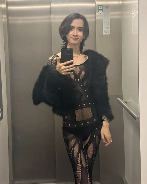 Alex in a black kinky party outfit taking a mirror selfie